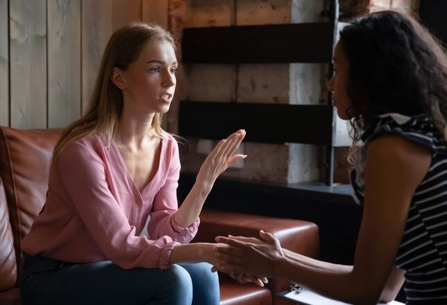 vrouw op een bank die in gesprek is met een andere vrouw